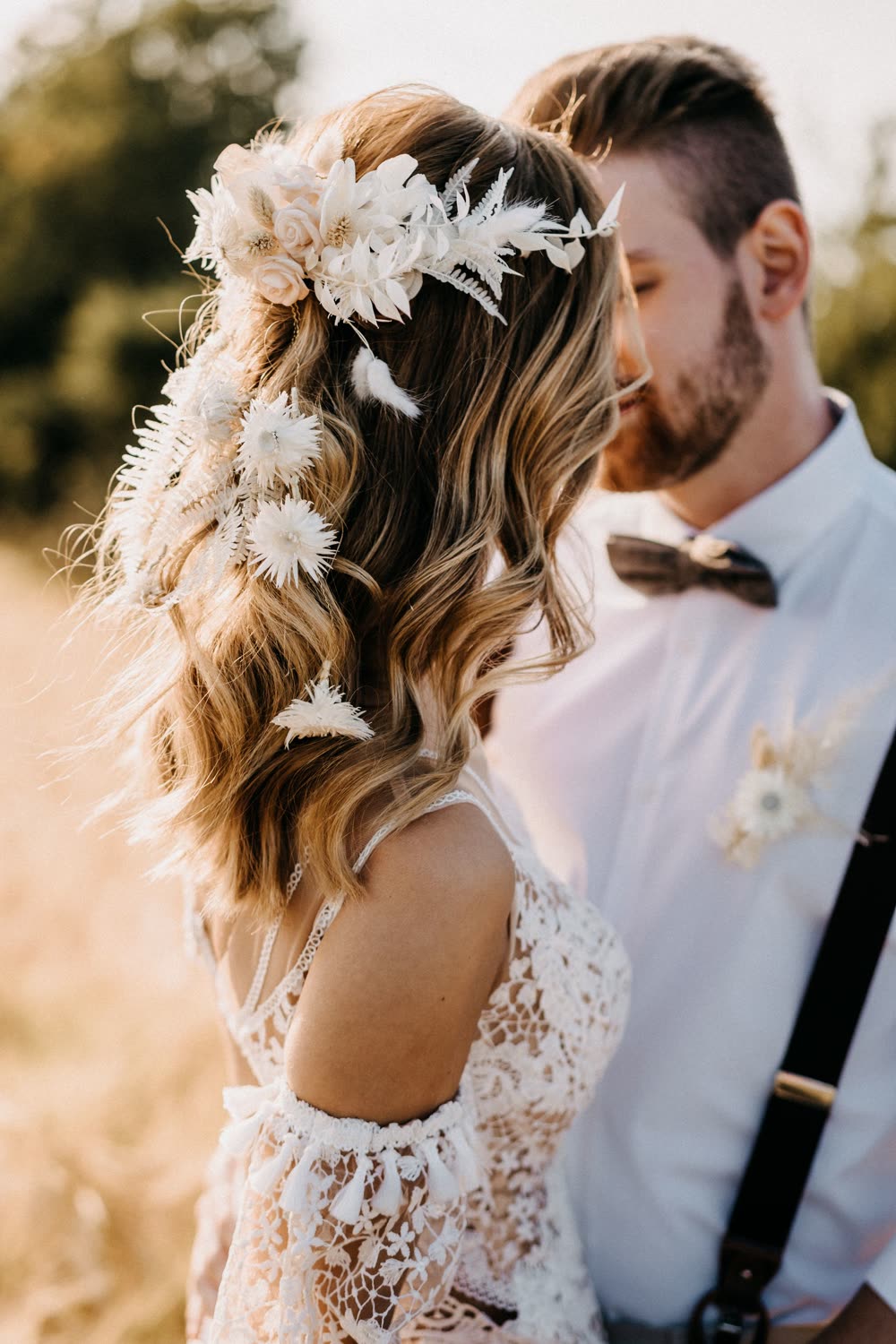 Braut mit Trockenblumen im welligen Haar, neben ihr der Bräutigam