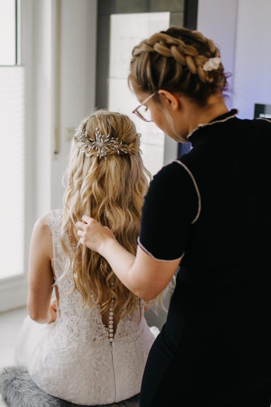 Eine Stylistin von Beautykram steckt einer Braut die Haare, von hinten gesehen
